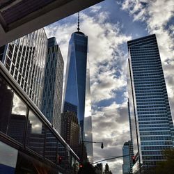 Low angle view of one world trade center against cloudy sky