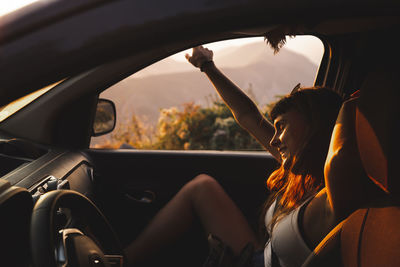 Happy young woman enjoying in car at sunset