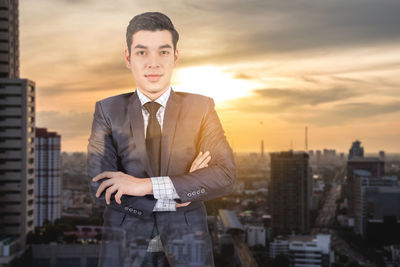 Double exposure of businessman and cityscape against sky during sunset