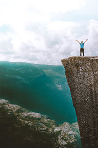 Man standing on rock by mountain against sky