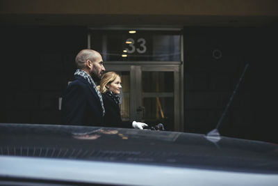 Side view of businessman and businesswoman walking by building