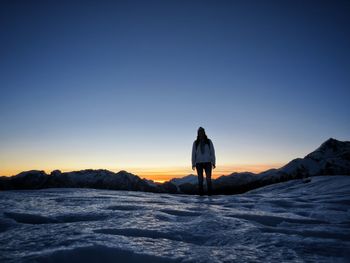 Rear view of man standing on snow covered landscape