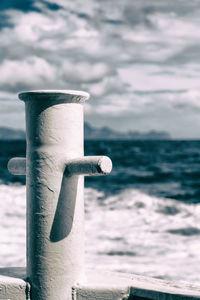 Close-up of wooden post at beach against sky