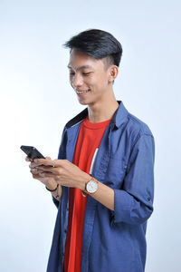 Potrait of handsome young asian man holding a smart phone and wear wristwatch with pretty smiling look at the phone