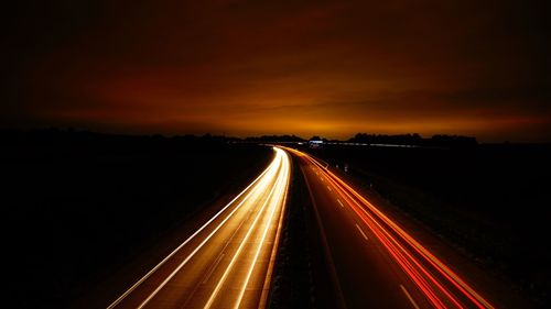 Light trails on road against sky at night