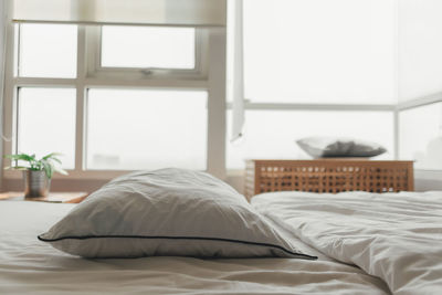 Comfortable loft white bedroom in bright day light.