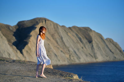 Full length of woman standing on mountain against sky