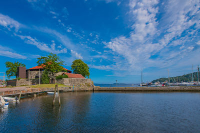 Scenic view of lake by building against blue sky