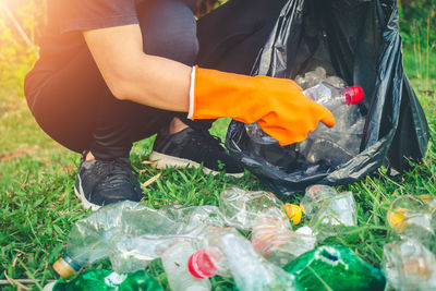 Low section of person cleaning garbage on field