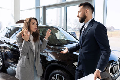 Saleswoman gesturing at colleague in car showroom