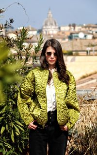 Portrait of young woman standing against plants