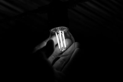 Close-up of hand holding lit candle in the dark