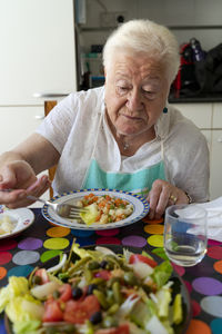 Old woman eating healthy food alone at home