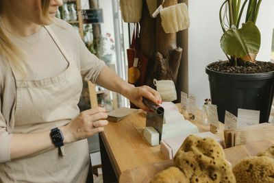 Woman cutting bar of soap on table in zero waste store