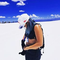 Young woman standing on snow against sky