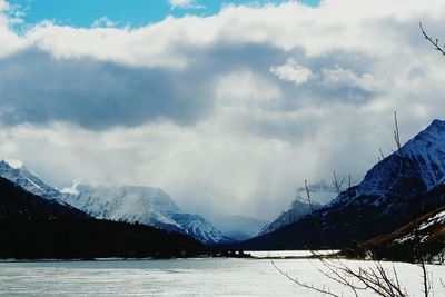 Scenic view of snow covered mountains against cloudy sky