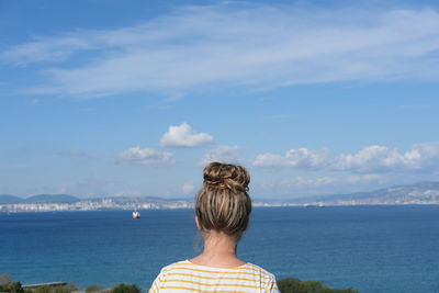 Teenager girl with messy bun looking at the sea. sity and ship on the horizon. sea bay view.