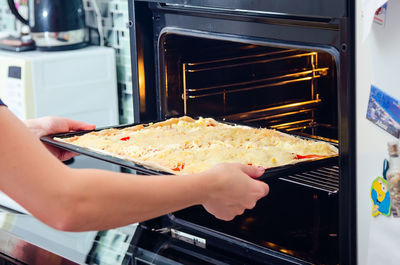 Cropped image of woman keeping food in microwave