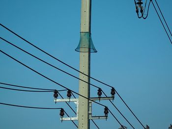 Low angle view of power lines against clear blue sky