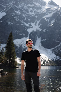 Portrait of young man standing against lake