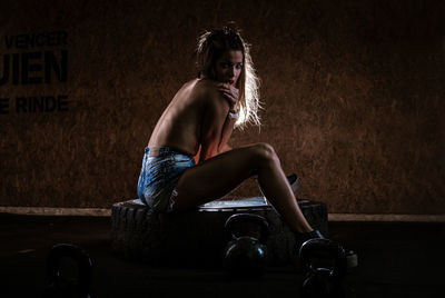 Portrait of young woman looking away while sitting on wall