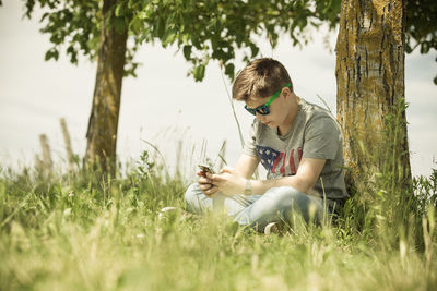 Teenage boy using phone while sitting at park