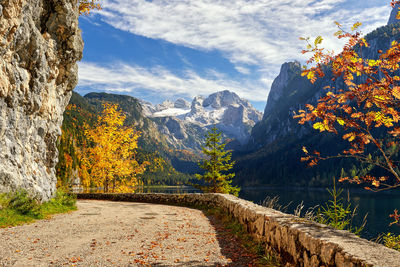 Footpath by mountains against sky during autumn