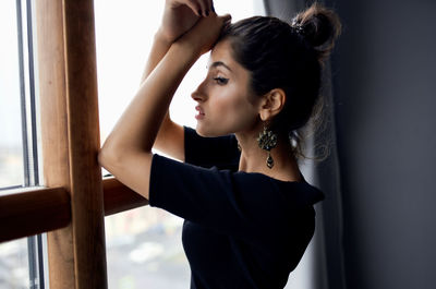 Side view of young woman looking through window