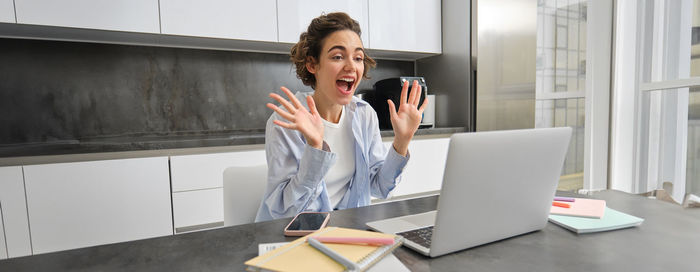 Young woman using mobile phone while standing in office