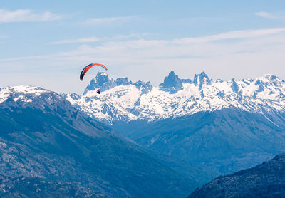 Low angle view of person paragliding against mountain range