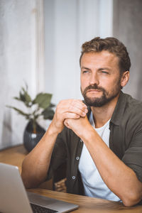 Side view of young man looking away while sitting at home
