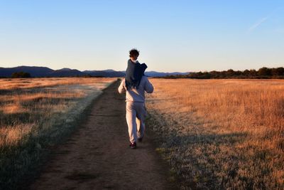 Full length rear view of man on field against sky