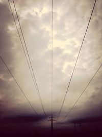 Low angle view of electricity pylon against cloudy sky