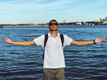 Young man standing at sea shore against sky