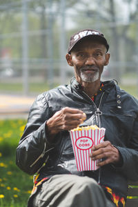Portrait of man holding camera outdoors
