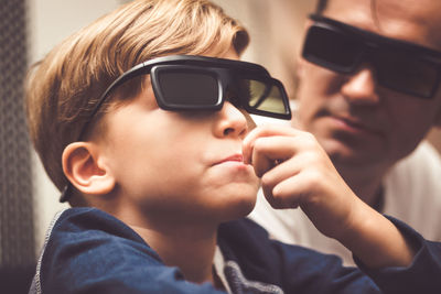 Father and son watching tv on sofa at home