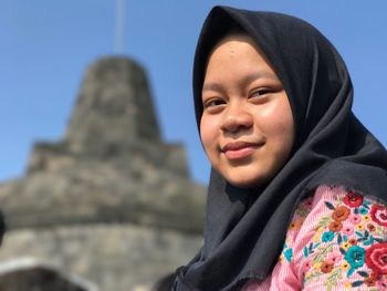 Low angle portrait of young woman against stupa at mertoyudan