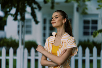 Young woman looking away while standing outdoors