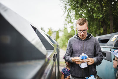 Young man using mobile phone while standing on car