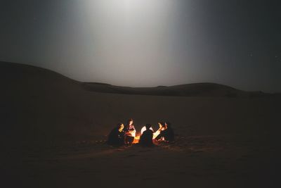 Friends at beach against clear sky at night