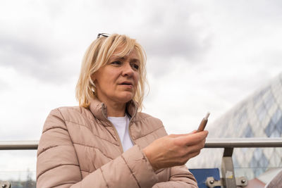 Woman holding electric cigarette against sky