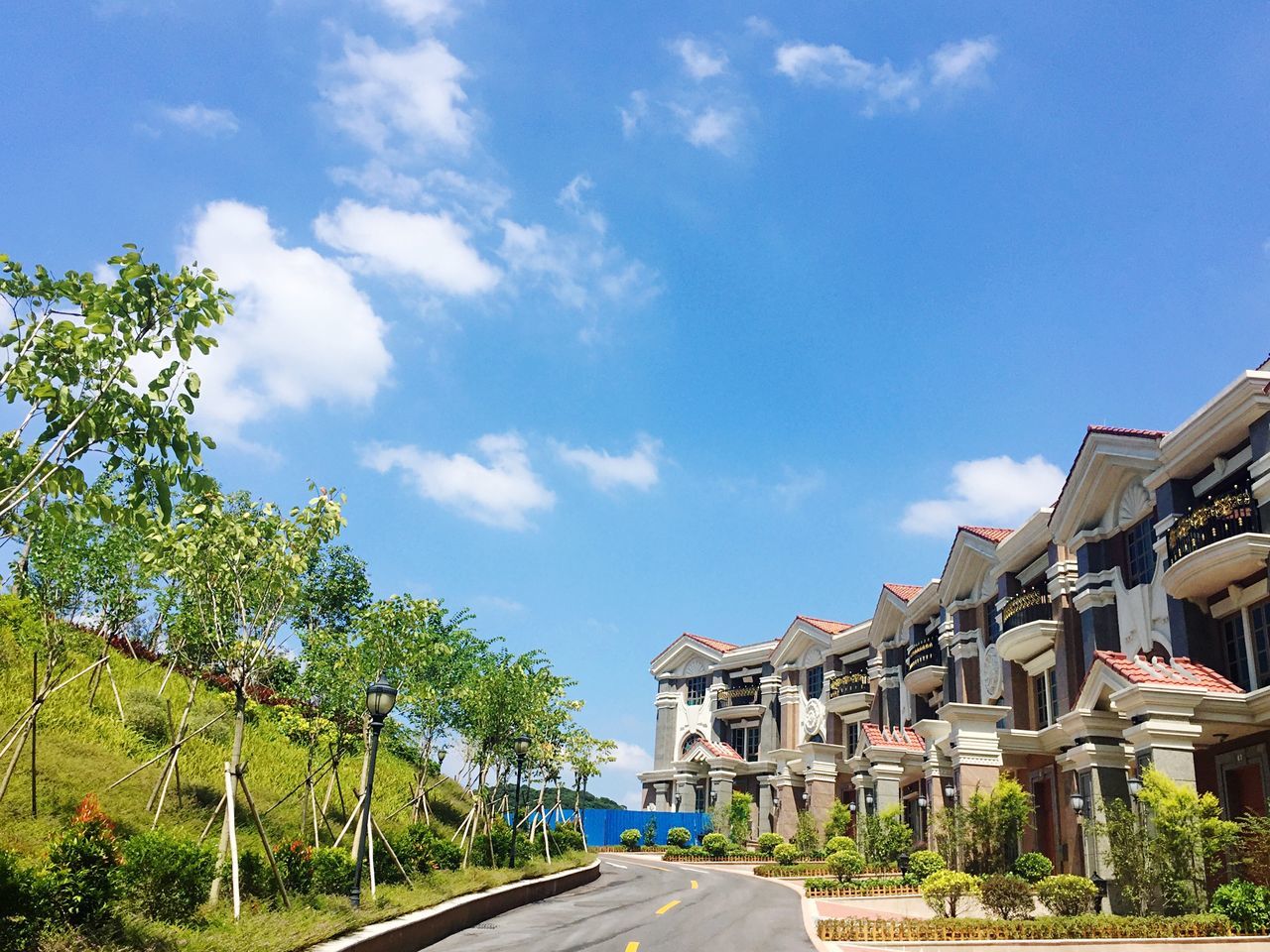 tree, architecture, built structure, building exterior, road, sky, the way forward, transportation, day, long, blue, cloud, diminishing perspective, outdoors, growth, green, footpath, countryside, solitude, vanishing point, remote, green color, tourism, tranquility, no people