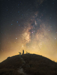 Silhouette man standing on field against sky at night