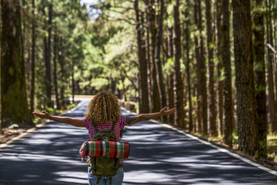 Rear view of woman walking on road in forest