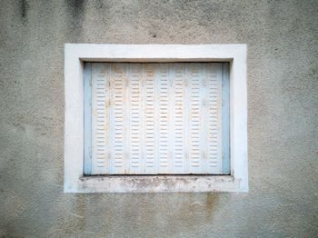 Close-up of white metal window on building wall