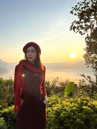 Portrait of young woman standing against sky during sunset