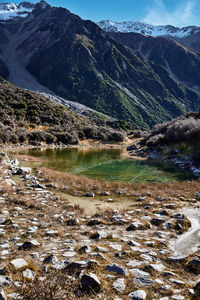 Scenic view of stream by mountains against sky