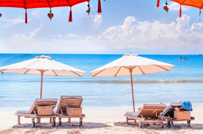 Deck chairs on beach against sky