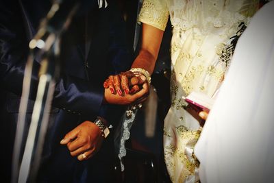 Midsection of couple holding hands at wedding ceremony