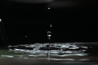 Close-up of drop falling in container at night